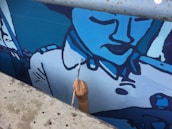 A close-up of a local artist painting a mural on a city wall.