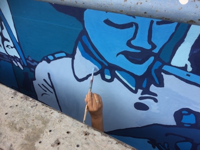 Close-up of hands painting a mural that tells a local story.