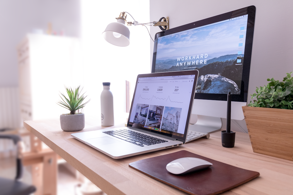 MacBook Pro na mesa ao lado do iMac branco e do Magic Mouse