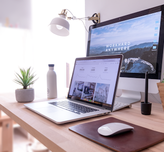 MacBook Pro on table beside white iMac and Magic Mouse