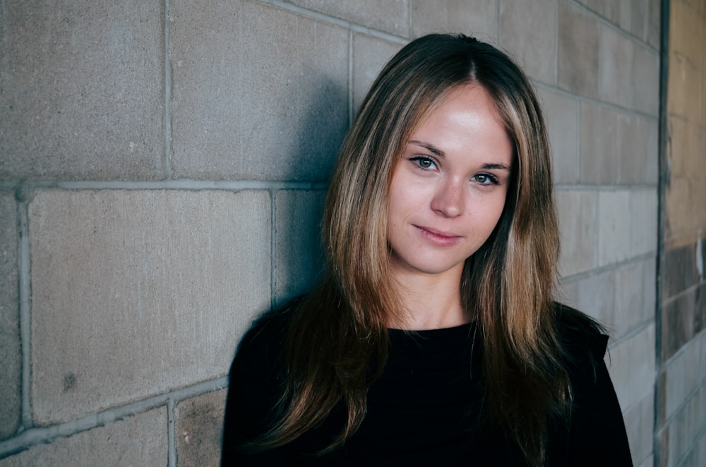 woman leans on gray concrete wall