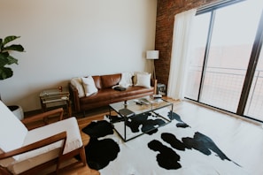 A sleek, modern cowhide leather sofa in a bright living room with natural light.