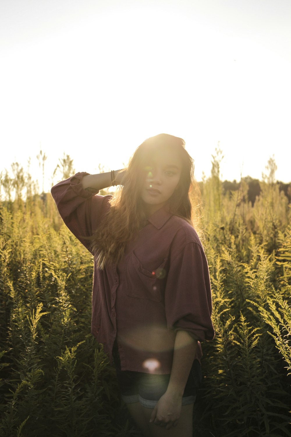 woman standing near green grass field wearing brown button-up long-sleeved dress shirt