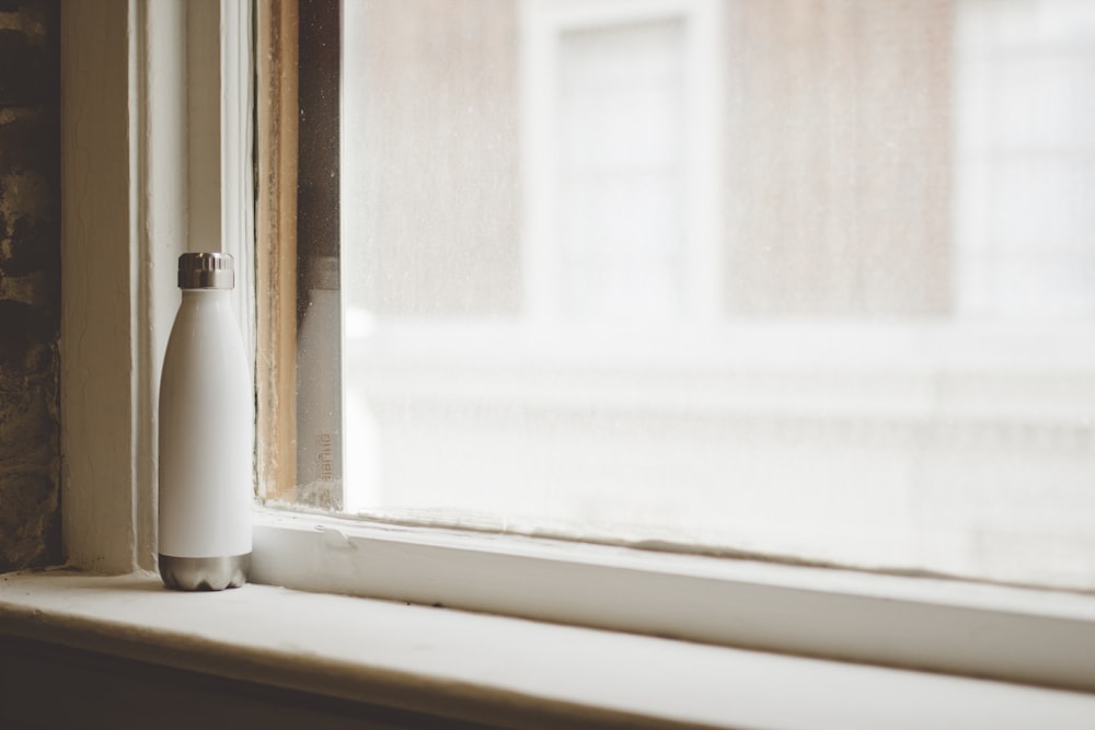 gray and white vacuum flask beside window frame