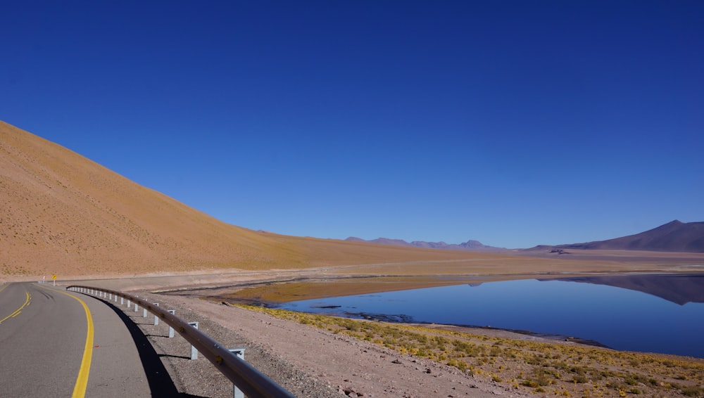 gray concrete road beside calm body of water