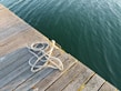 A neatly coiled fishing net resting on a wooden dock by a calm river