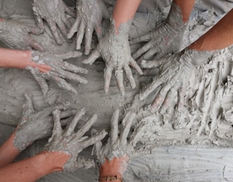 people's hand on gray mud