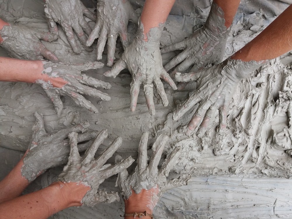 La mano de la gente sobre el barro gris