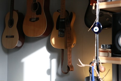 Warmly lit recording studio corner with acoustic guitars hanging on the wall.