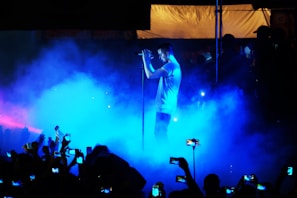 A vibrant snapshot of a singer mid-performance under electric blue stage lights.