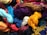 A vibrant assortment of dyed yarns is piled together, featuring a variety of colors including bright yellows, reds, blues, purples, and more.