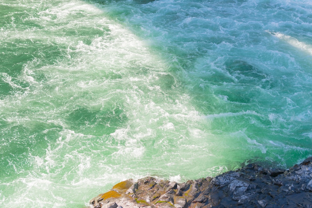 photo of body of water near gray stone