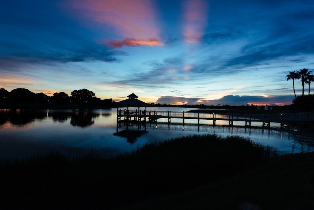 a dock in a lake at sunset with palm trees in the background