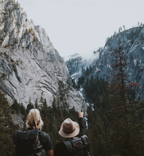 two human standing between the mountains