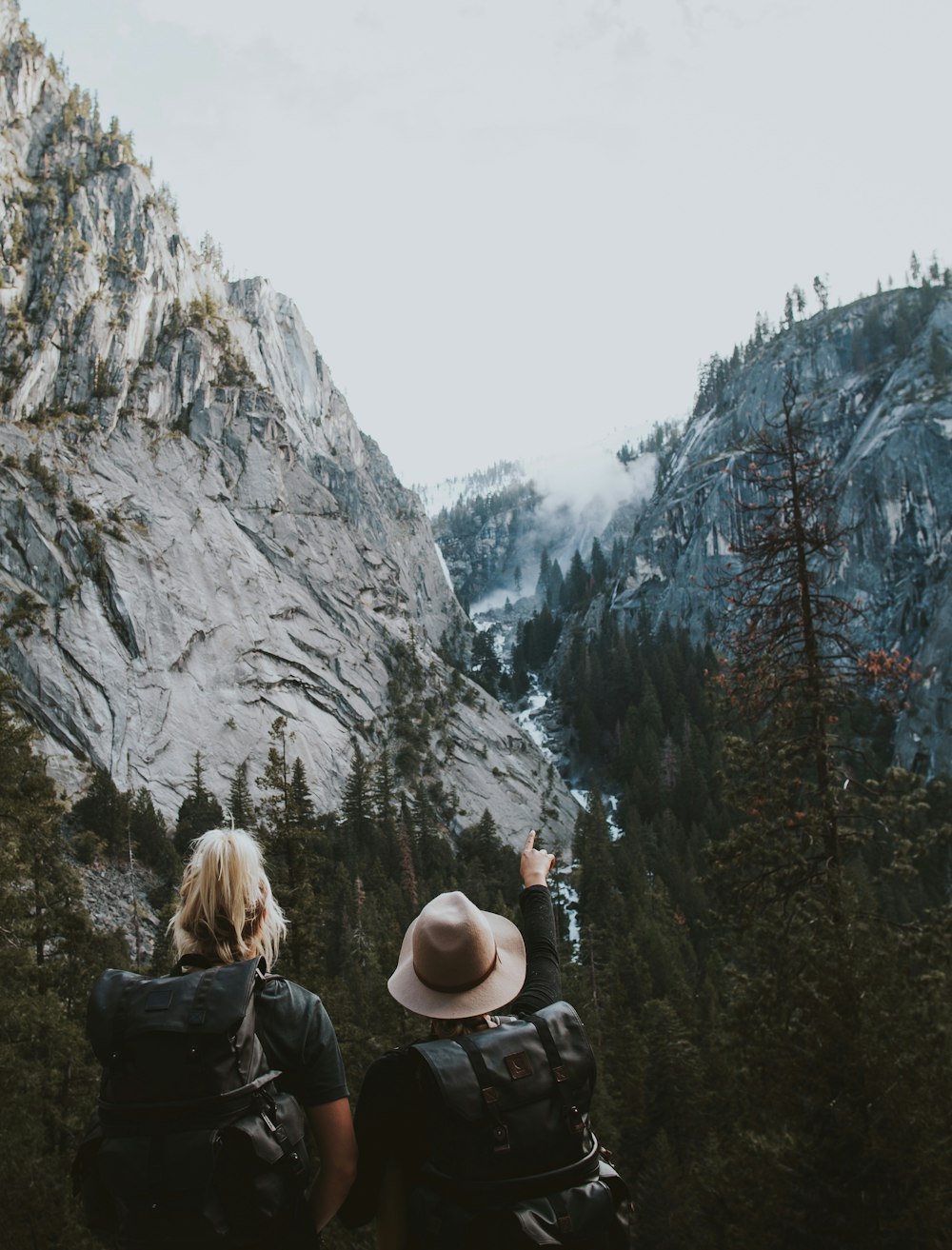two human standing between the mountains