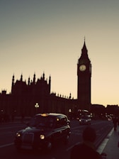 A taxi driving through iconic UK landmarks during sunset.