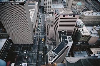Aerial view of a cityscape featuring tall office buildings with signage, intersecting roads, and urban infrastructure.