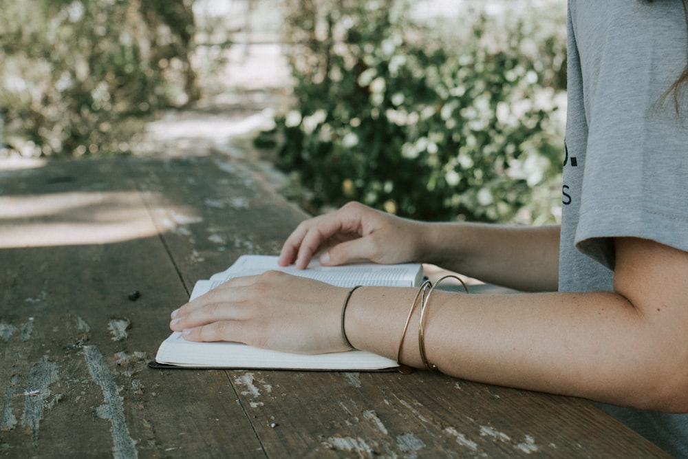 person holding book white sitting in front of desk