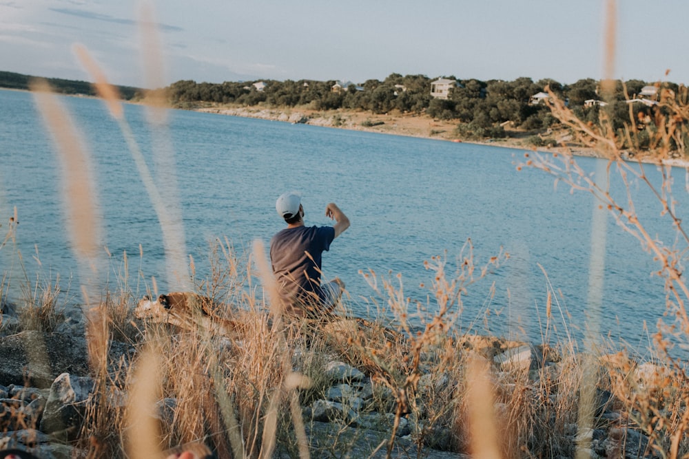 man sitting at rocks near body of water