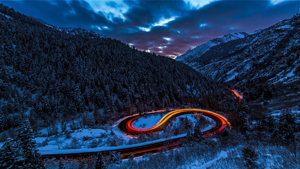 timelapse photography of curved road between mountain with trees