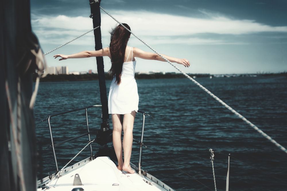 woman standing at the edge of a boat that is sailing in ocean