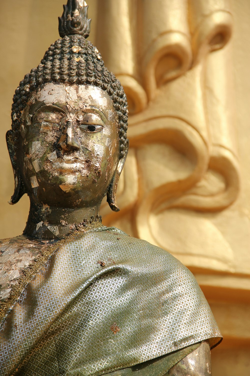 fotografía de enfoque selectivo de la estatua de Buda cerca de la pared de hormigón beige