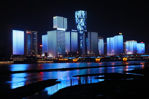photography of lighted buildings reflecting on water