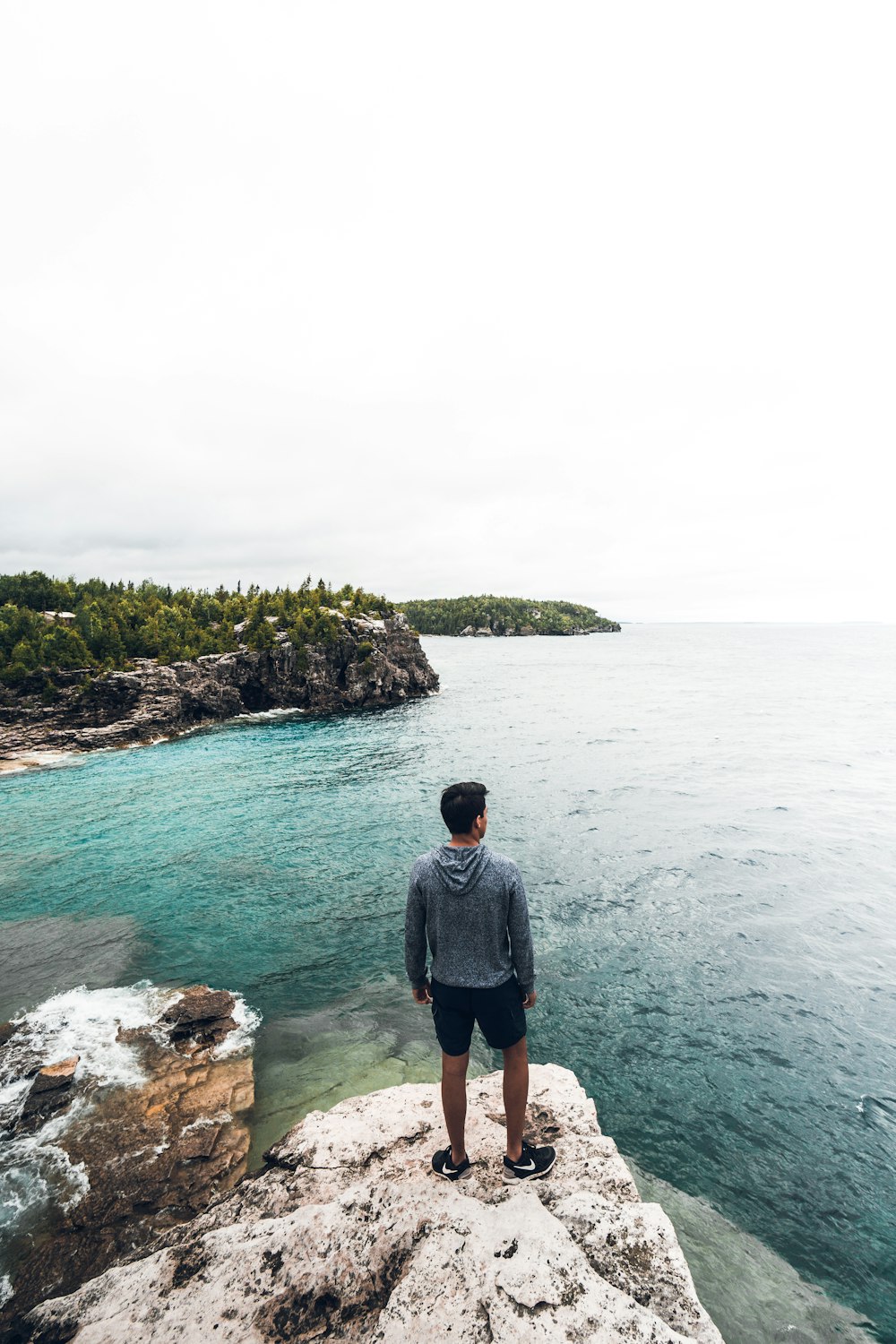 homme debout sur le rocher blanc et brun voyant l’horizon pendant la journée