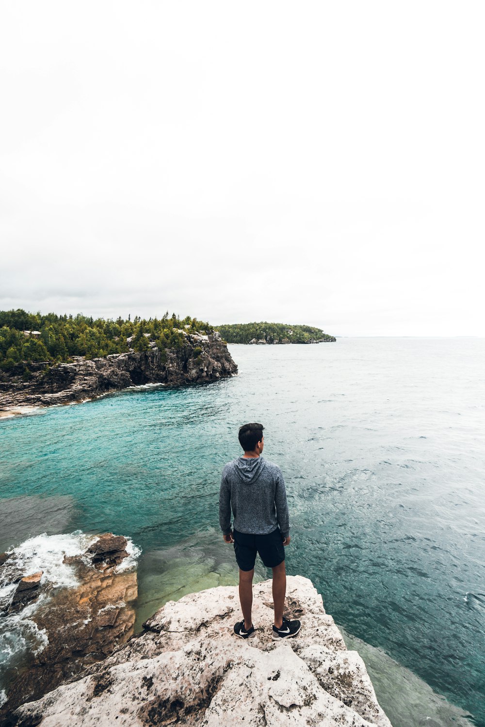 homem em pé na rocha branca e marrom vendo o horizonte durante o dia