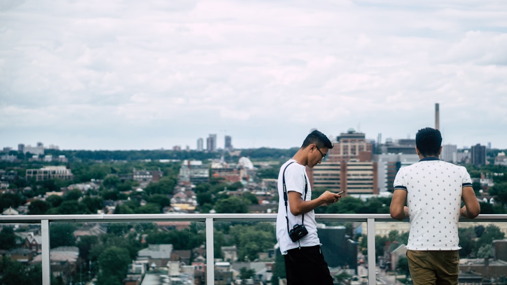 Dois homens estão em uma varanda com vista para a paisagem urbana de Toronto.