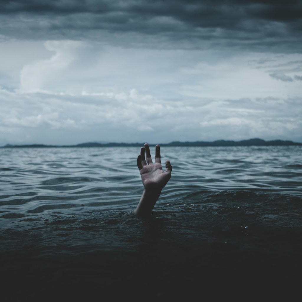 hand reaching up through surface of dark water