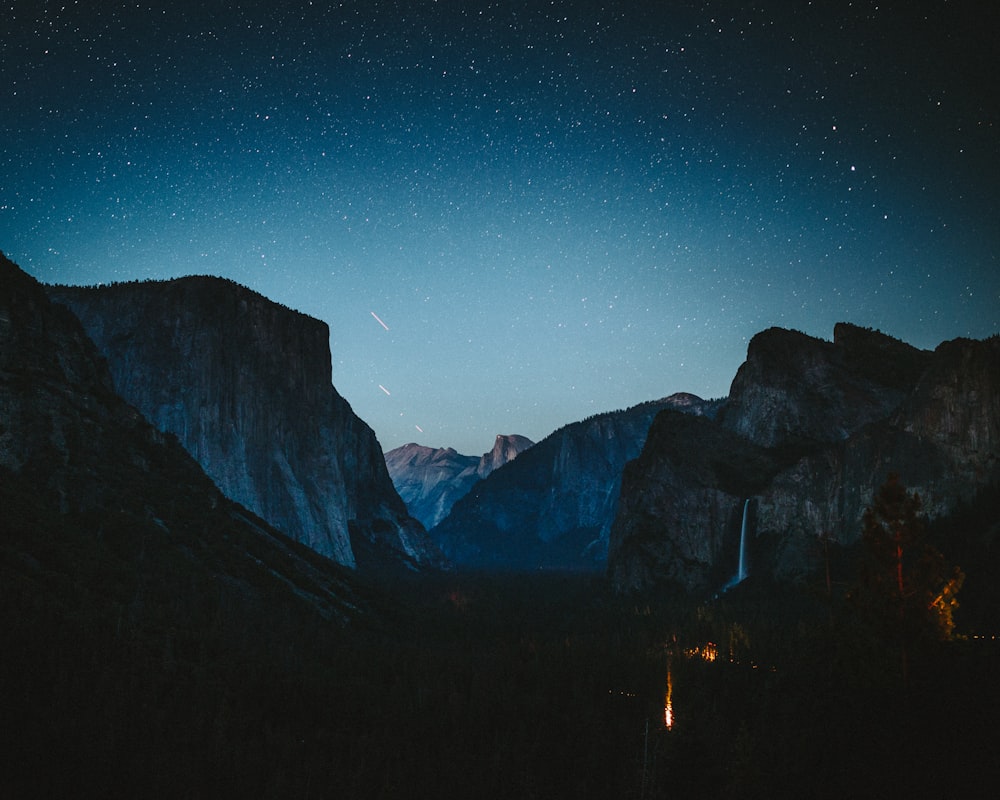 silhouette of mountains under blue sky during night time