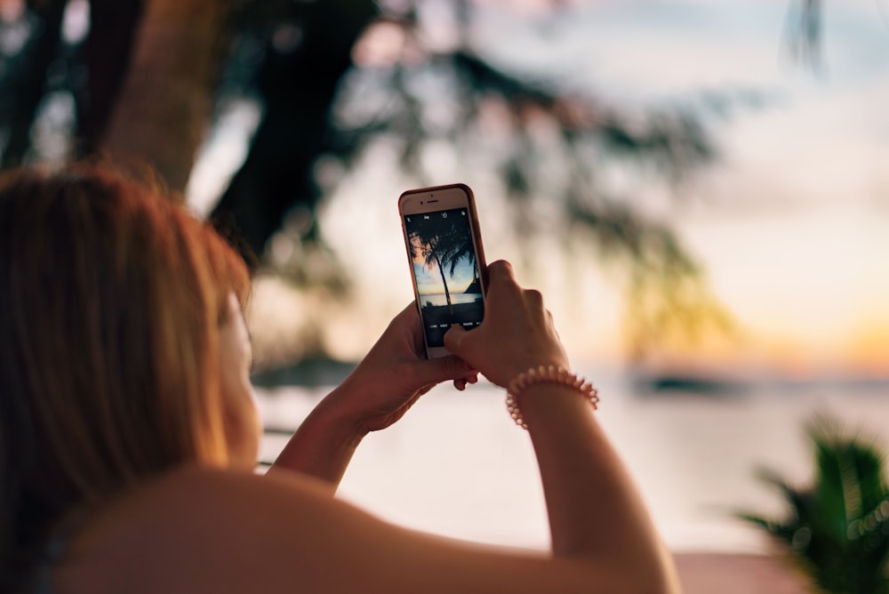 Donna che scatta foto di un albero tropicale verde in spiaggia