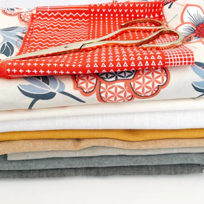 Stack of neatly folded patterned fabric pieces with scissors and thread nearby