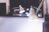 Close-up of a sleek 3D printed lamp casting warm light on a wooden desk.