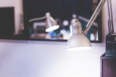 Close-up of a sleek 3D printed lamp casting warm light on a wooden desk.