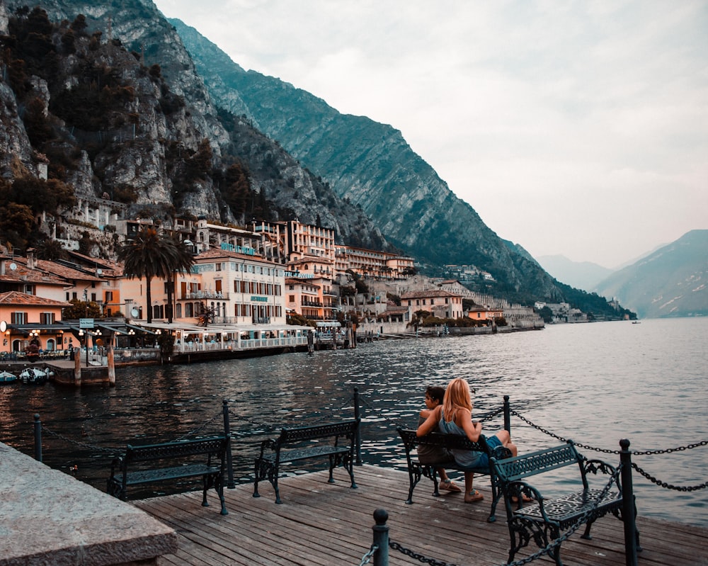 a woman sitting on a bench next to a body of water