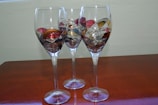 A set of wine glasses decorated with vibrant resin designs sitting on a wooden table.