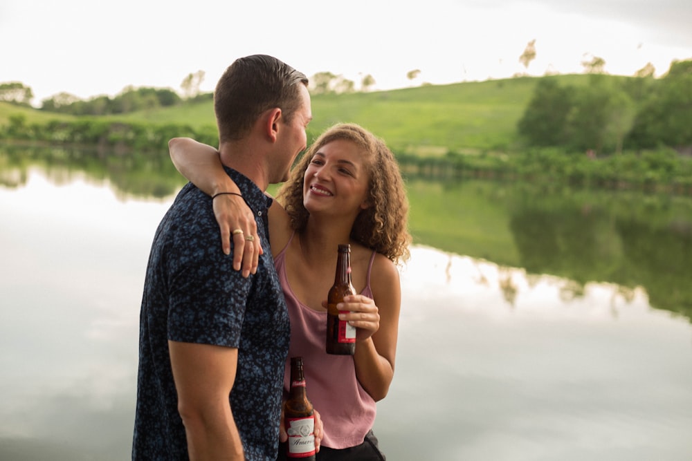 woman holding beer bottle while hugging guy