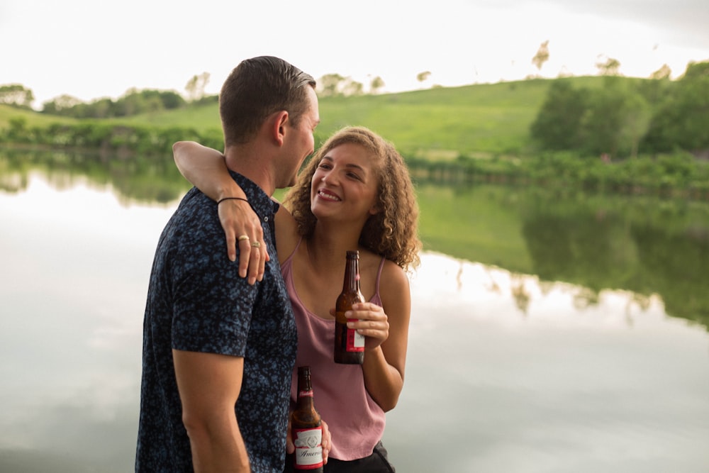 femme tenant une bouteille de bière tout en étreignant un gars