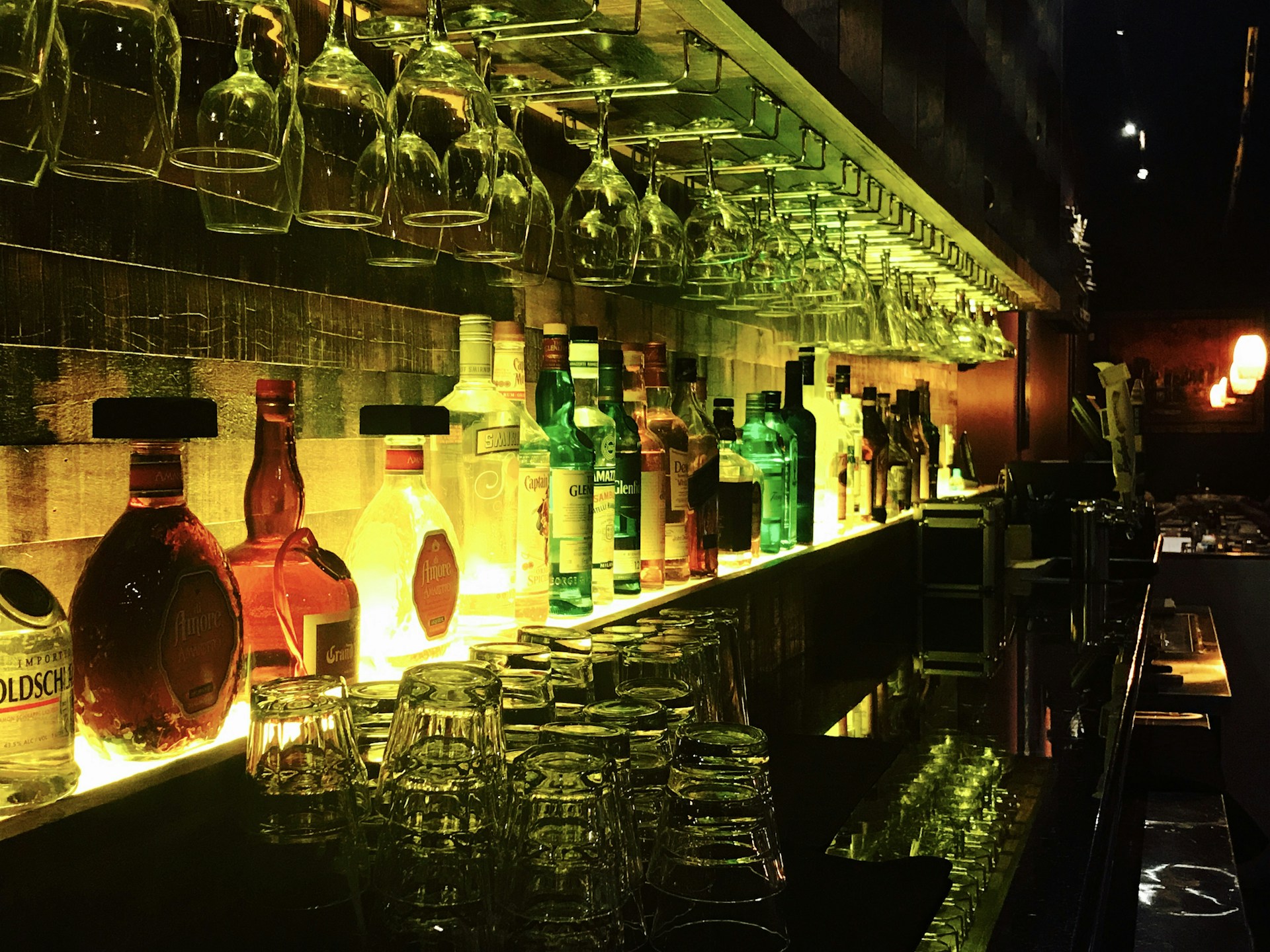 A vibrant display of assorted wines and liqueurs from the bar's well-stocked bodega, set against a backdrop of warm wooden shelves.