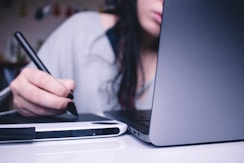 woman using drawing pad while sitting in front of laptop
