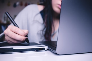 woman using drawing pad while sitting in front of laptop