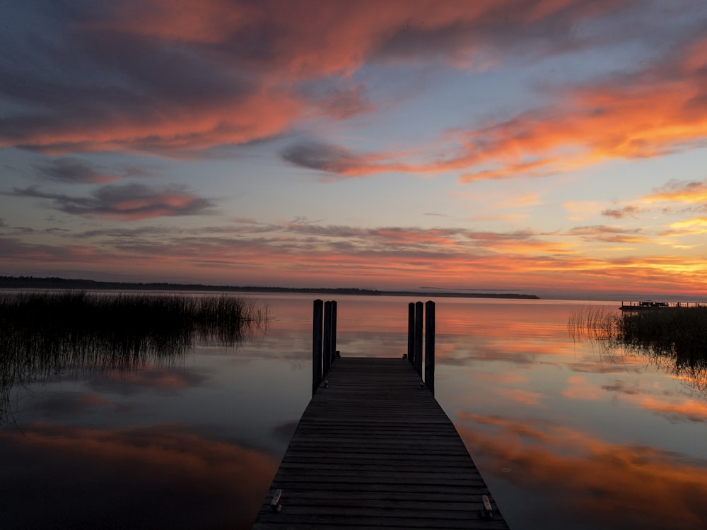 black wooden dock on body of water during golden hour