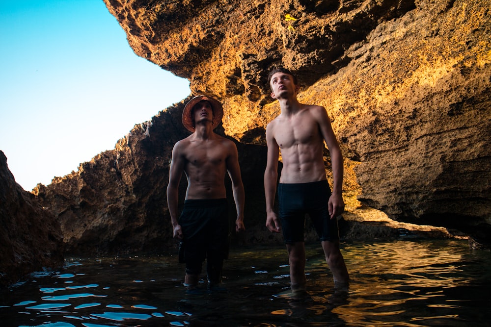 two men standing near brown rock formation