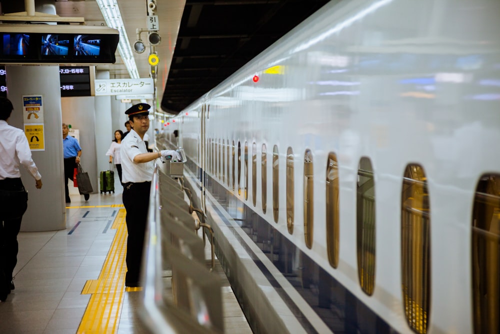 man standing behind railing of subway station platform