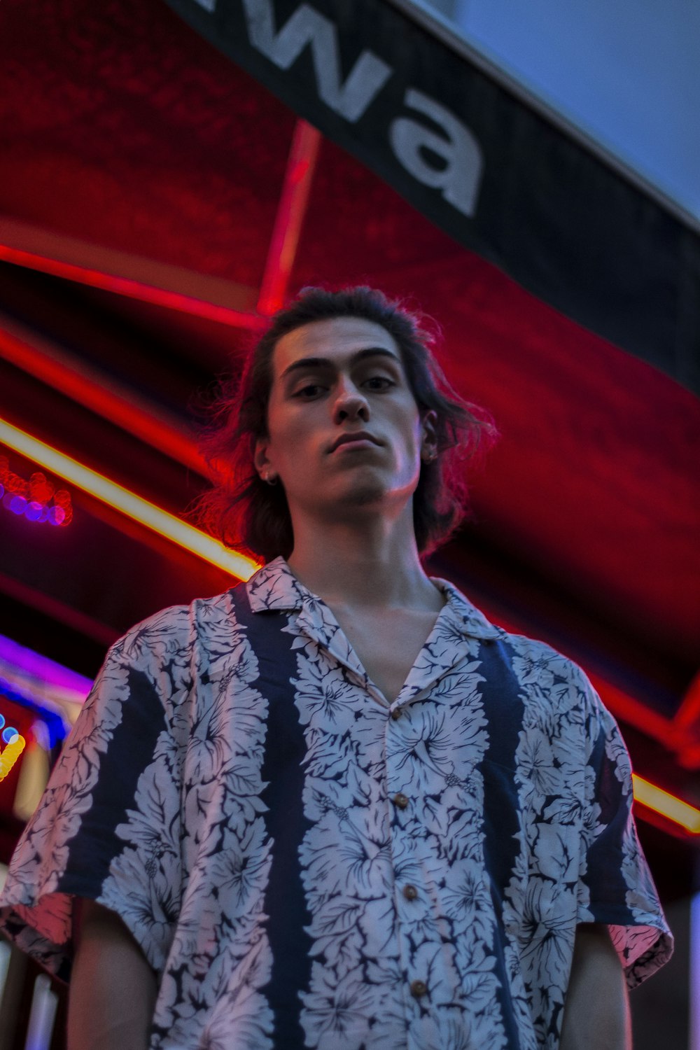 man wearing white and black floral button-up short-sleeved collared shirt beside store