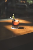 brown beverage with olives and herb in rocks glass in macro photography