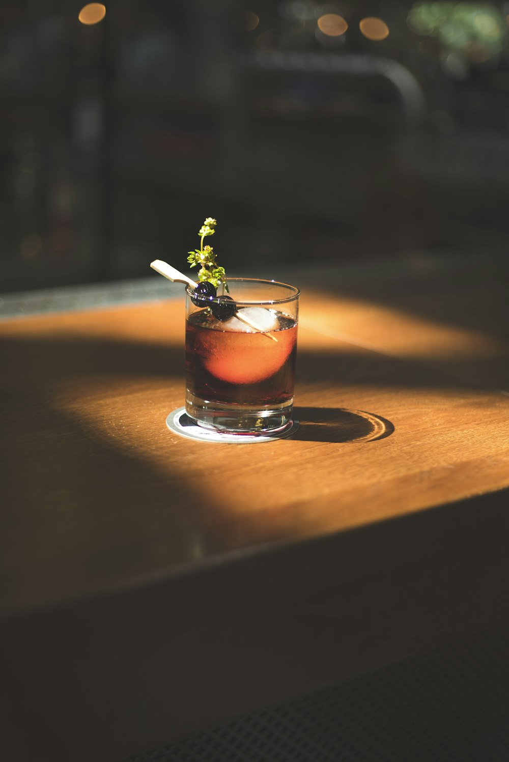 brown beverage with olives and herb in rocks glass in macro photography