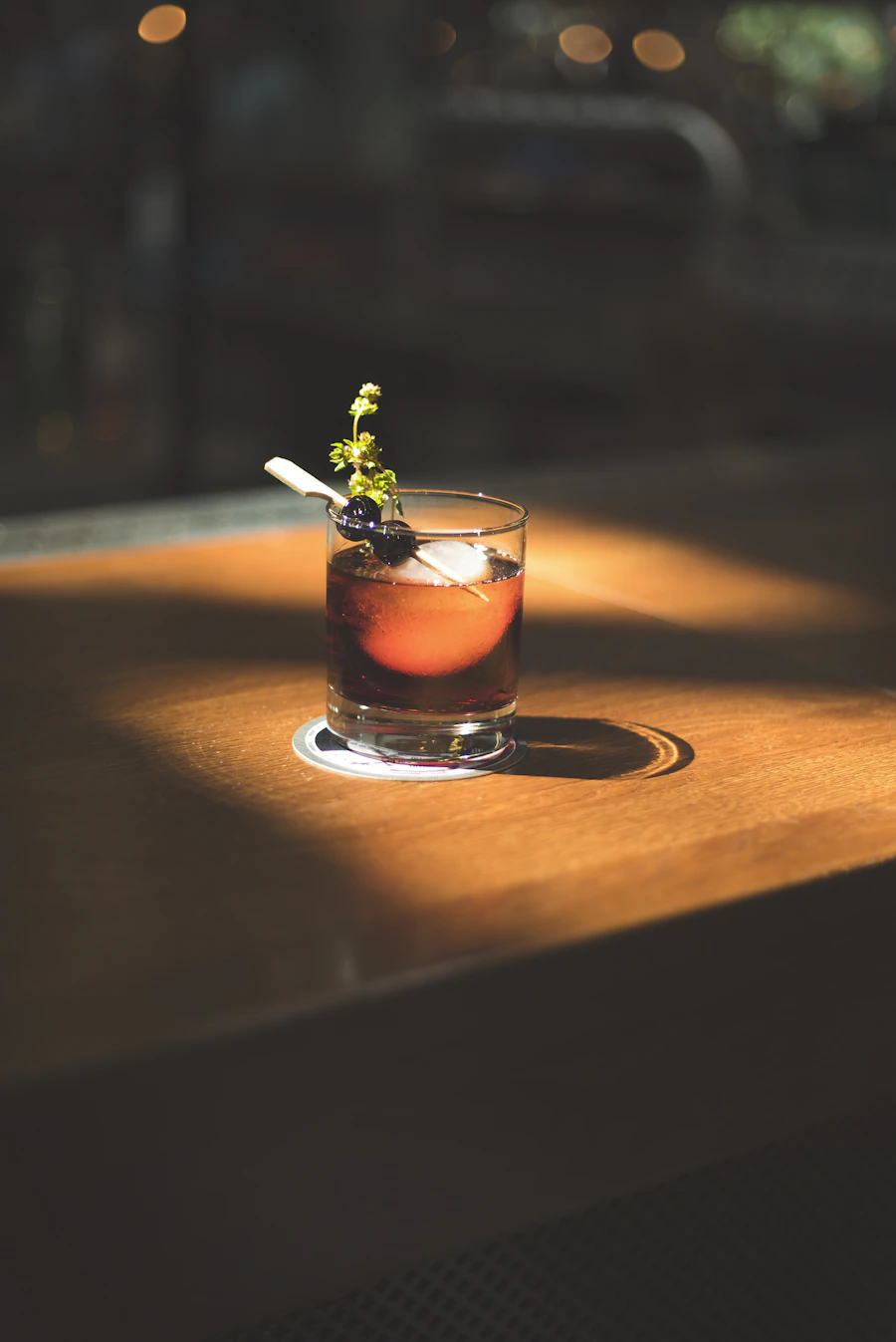 A spirit-forward cocktail with an olive in a rocks glass on the bar